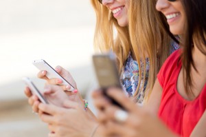 Three girls chatting with their smartphones at the campus