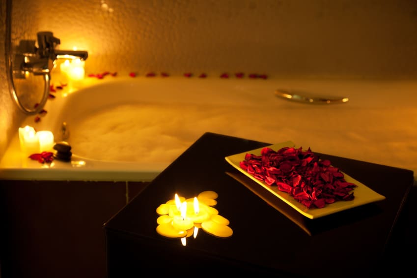 Romantic bathtub ready with candlelight and red petals