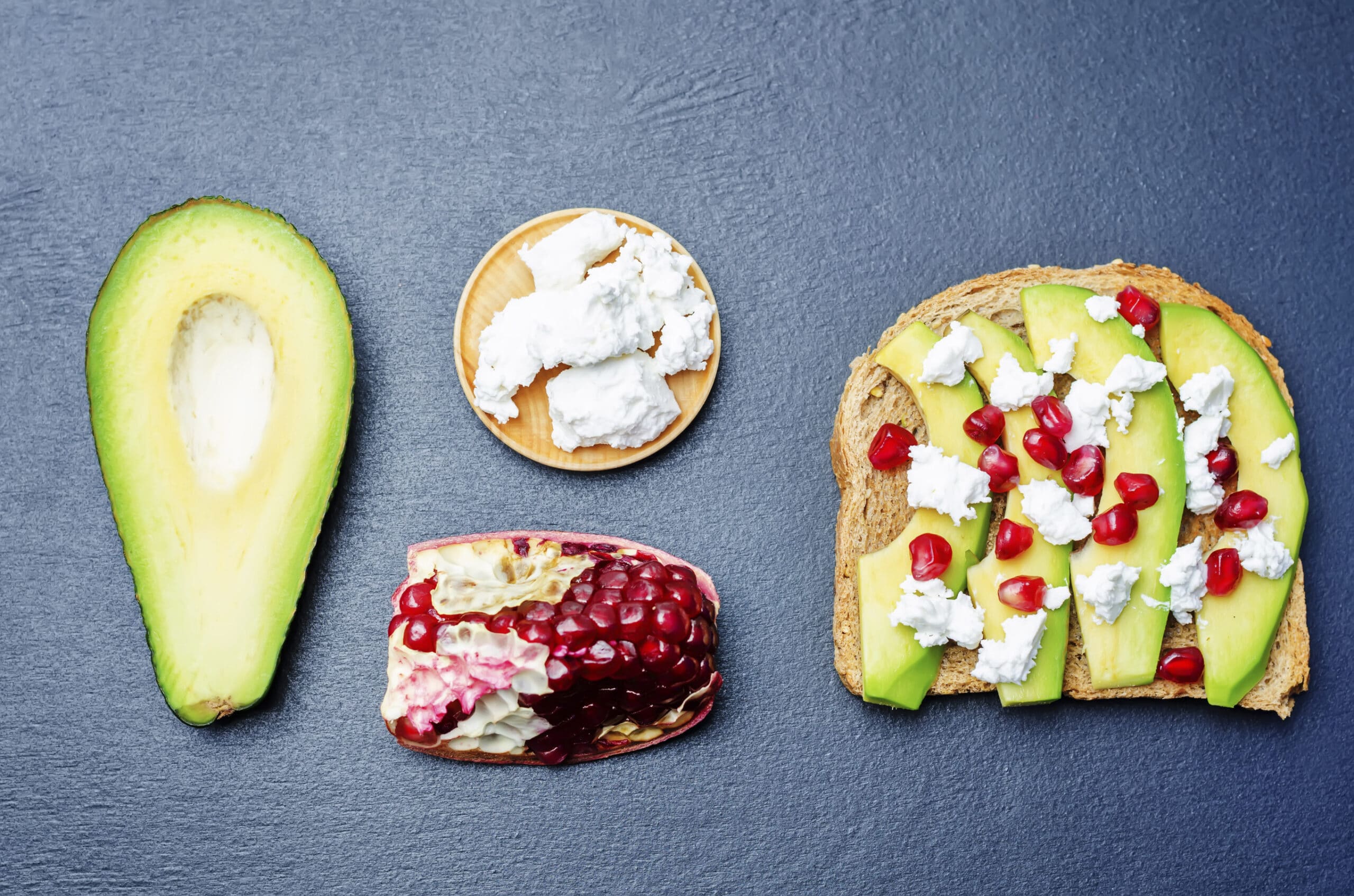 Sandwich with avocado, feta and pomegranate on a black background. toning. selective focus