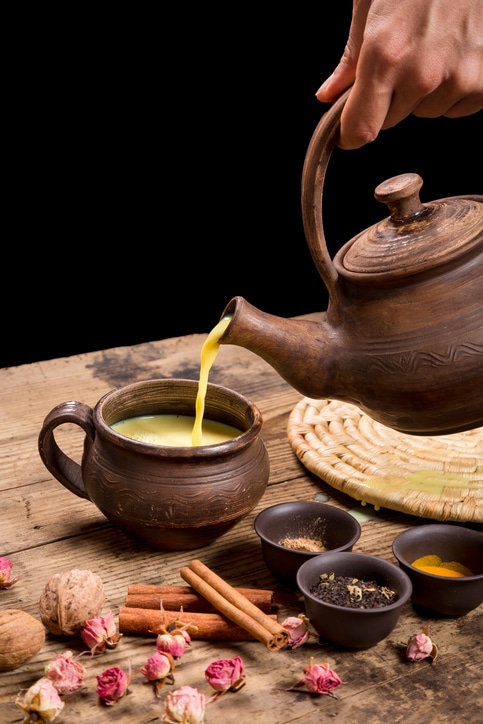 Pouring masala tea from dark ceramic pot