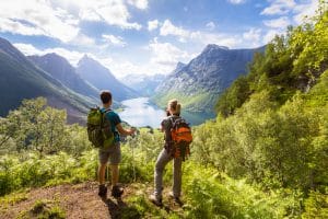 Two hikers at viewpoint  in mountains with lake, sunny summer